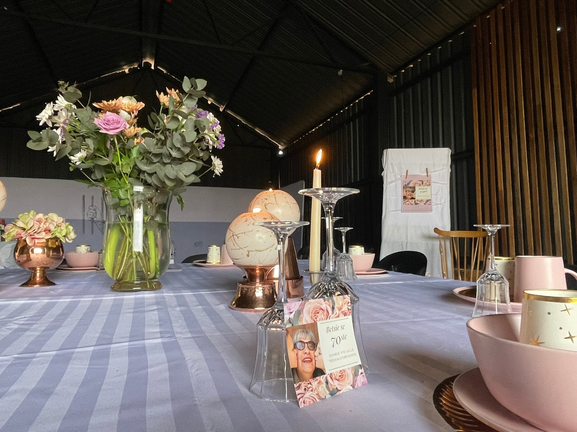 Beautifully styled birthday table inside the Solid Ground hall — fresh flowers, candles, copper accents and personalised photo cards