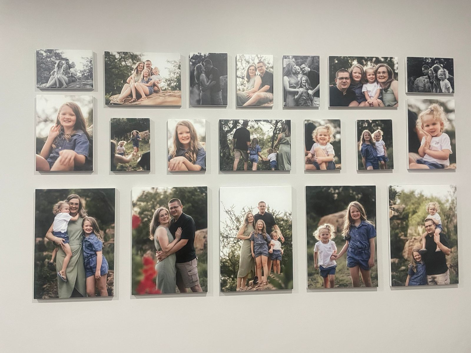 A wall of printed family photoshoot canvases displayed in a home