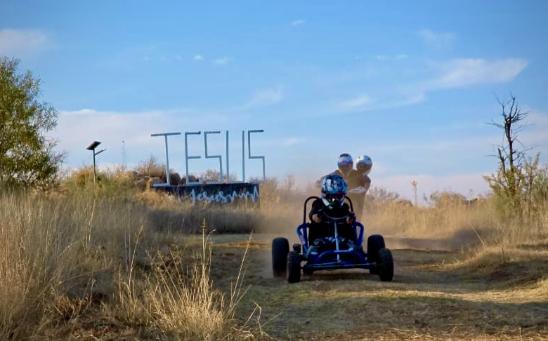 Go-kart riding past the JESUS sign on the trail