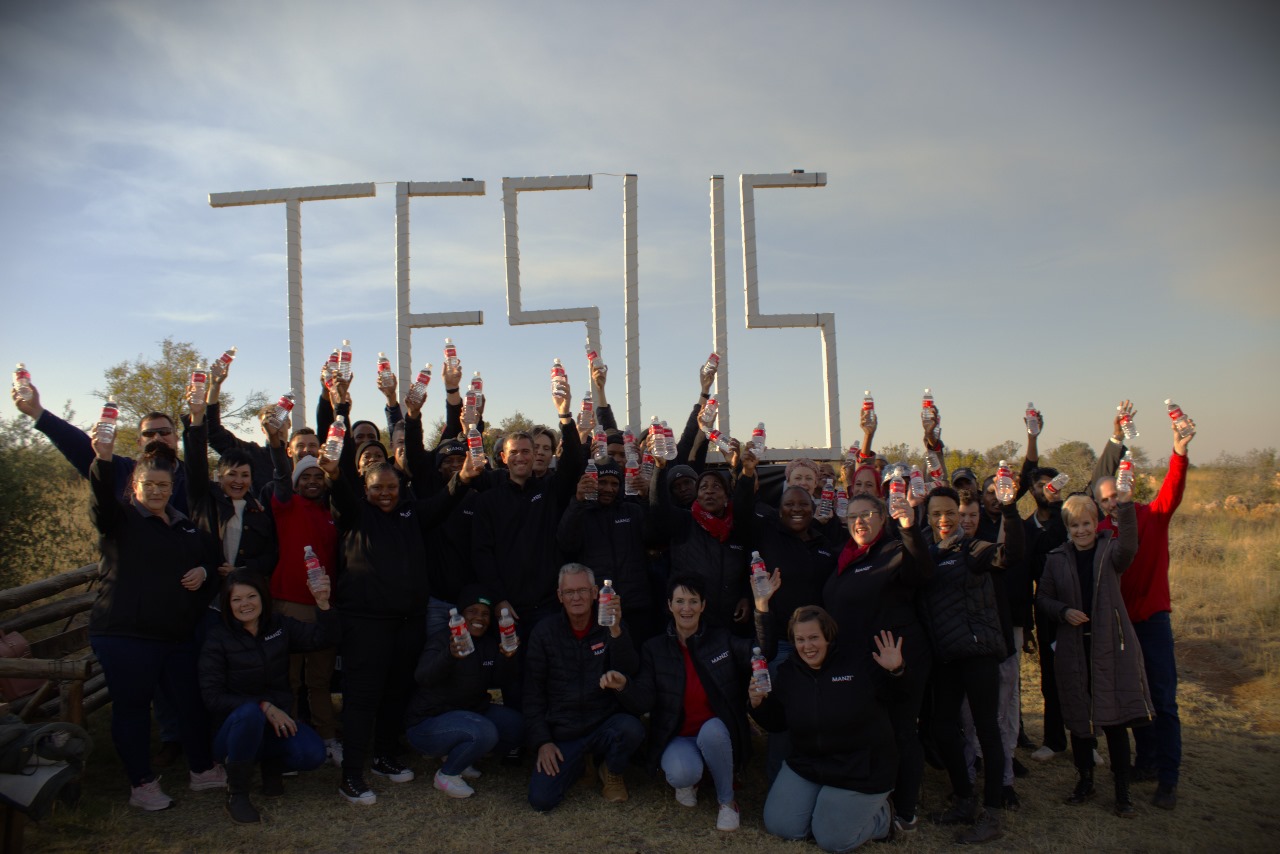 Manzi team holding water bottles at the JESUS sign
