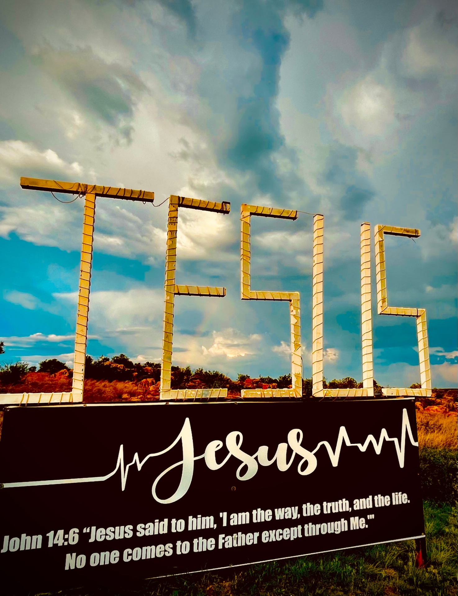 JESUS sign against a dramatic cloudy sky