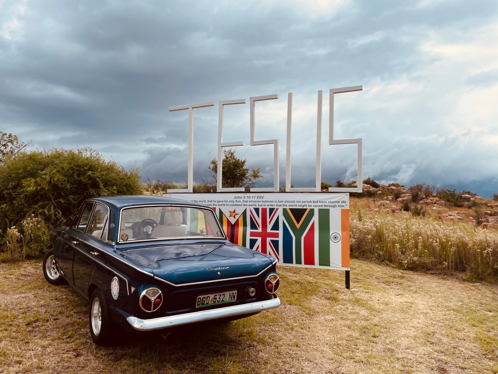Vintage blue Ford Cortina parked by the JESUS nations banner