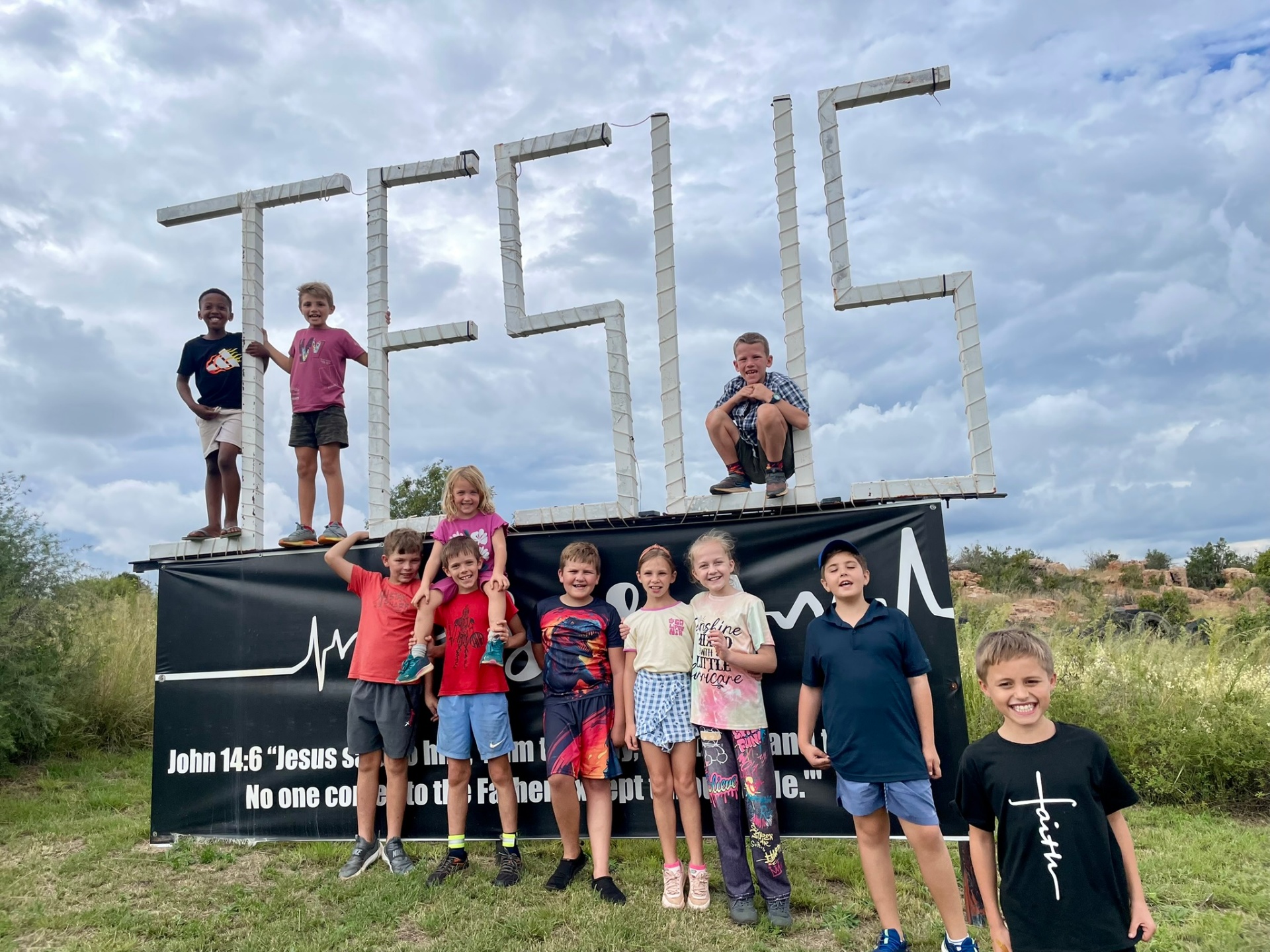 Group of children gathered at the JESUS sign