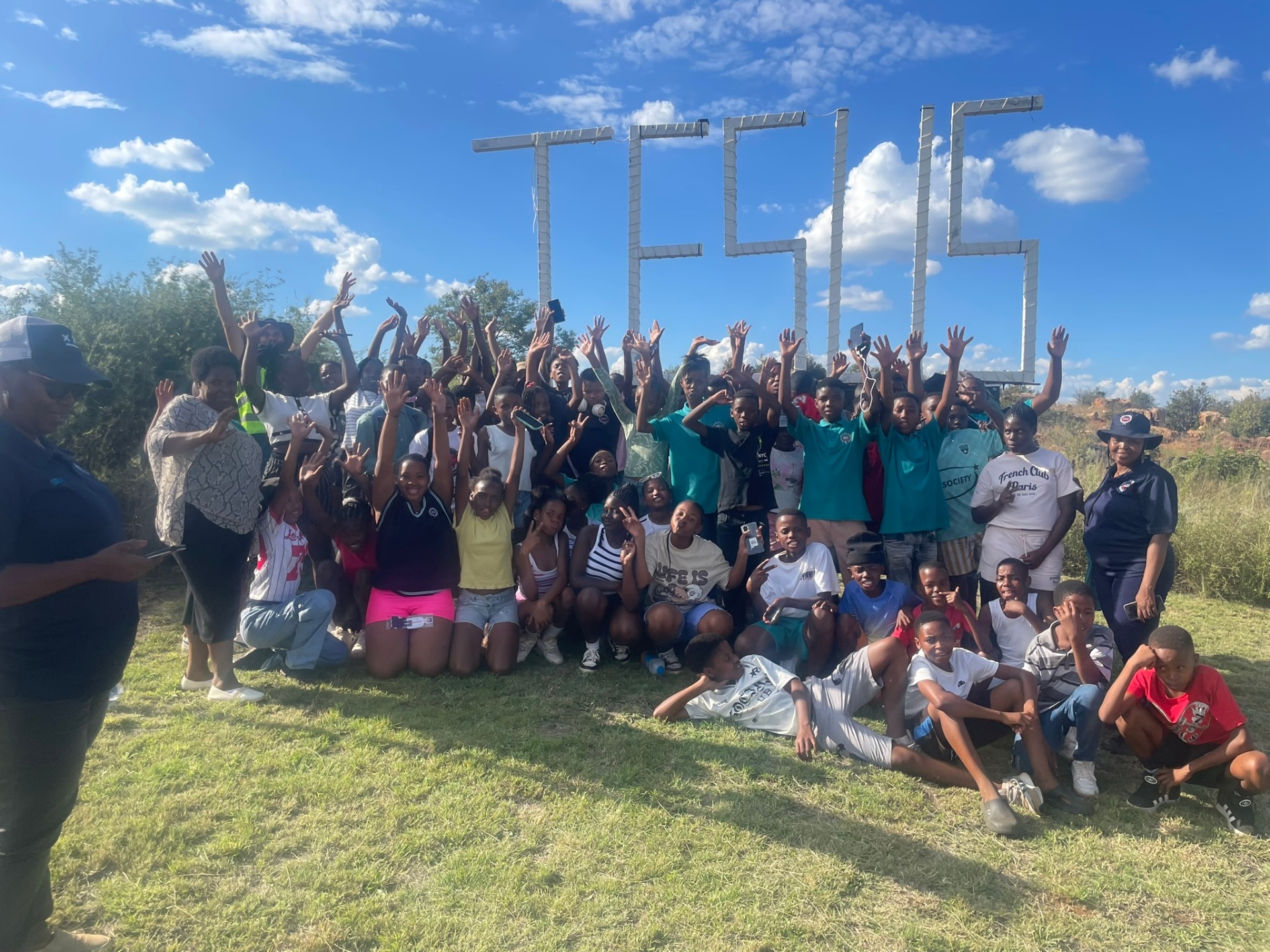 Large youth group celebrating with hands raised at the JESUS sign