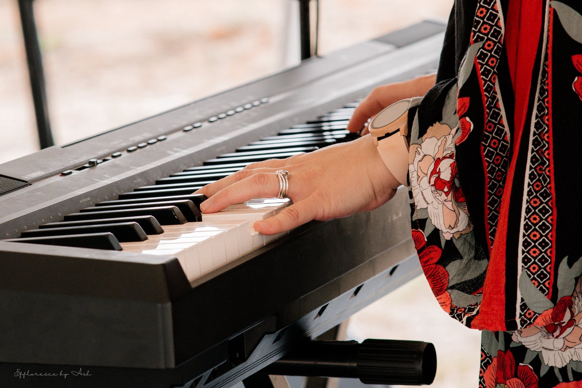 Hands playing a keyboard in a colourful floral dress