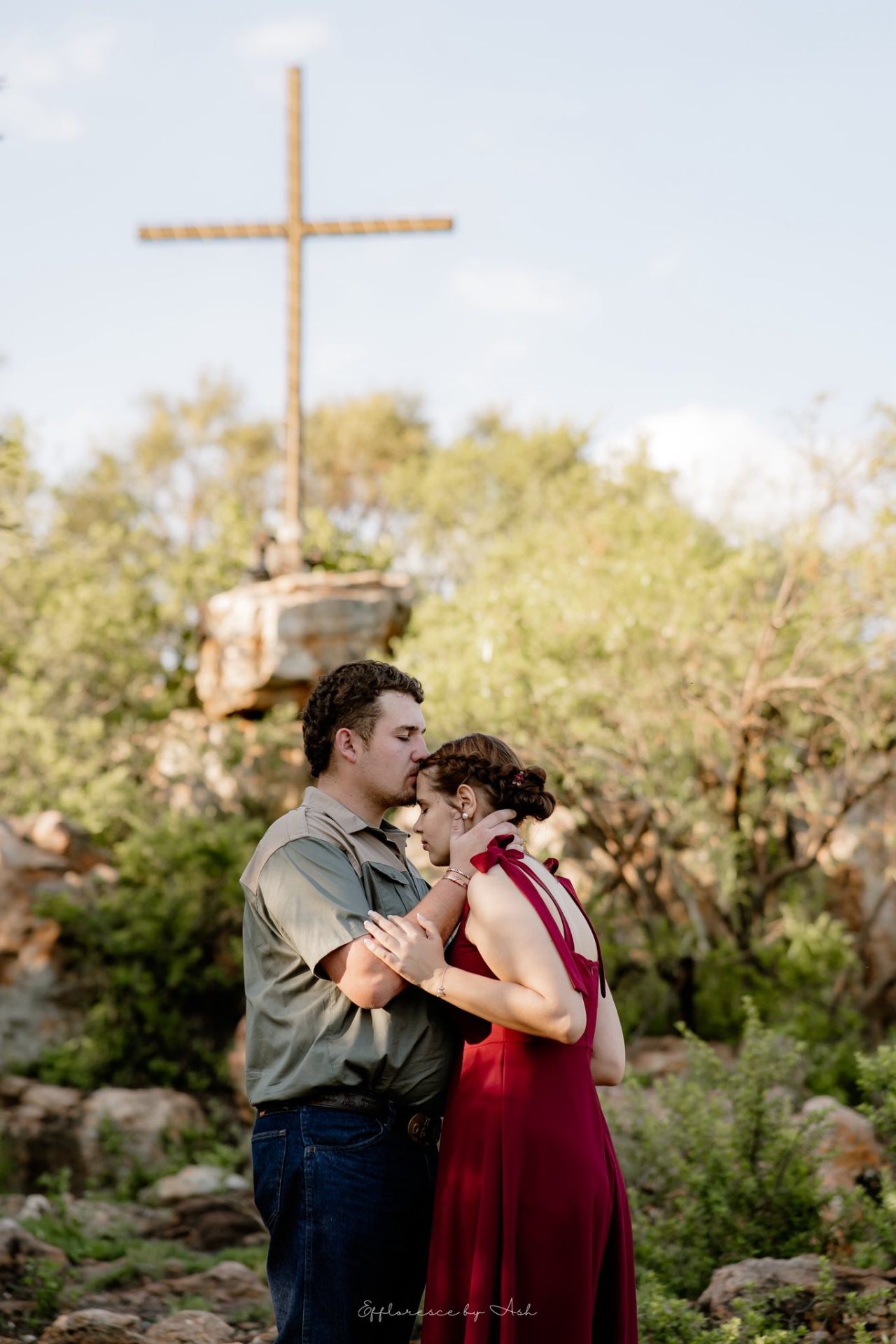 Couple embracing under the wooden hilltop cross