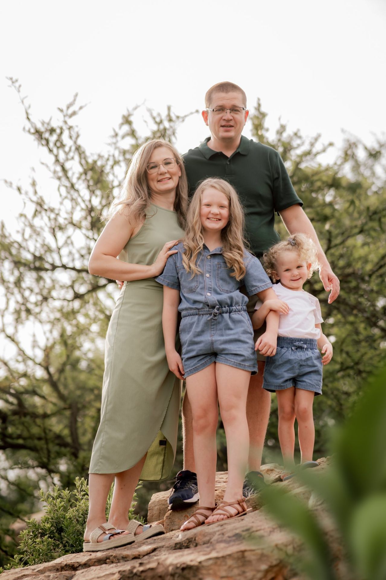 Family of four standing together on a rocky outcrop